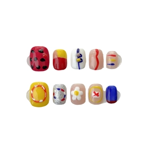 Faux ongles courts faits main avec motifs abstraits colorés et détails floraux