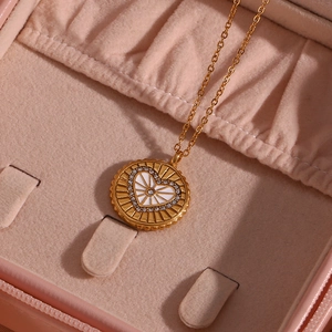 Gros plan d'un collier doré avec cœur en émail blanc et incrustation de zircons