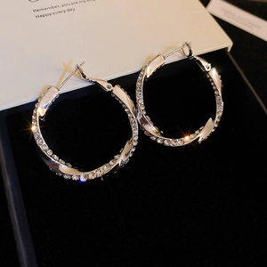 Macro shot of silver twisted hoop earrings with shimmering rhinestones on black velvet