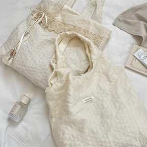 Close-up of cream textured canvas tote bags with elegant lace trim and tassel details