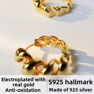 Macro shot of S925 sterling silver hoop earrings with twisted gold chain texture detail