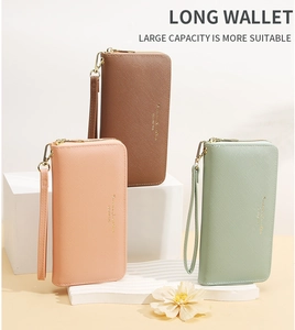 Three long zip-around wallets in pink, brown and mint green with wrist straps on pedestals