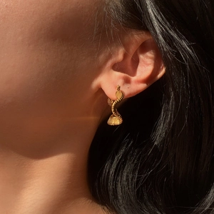 Close-up of stylish 18K gold plated snake-shaped earring worn on a female ear model