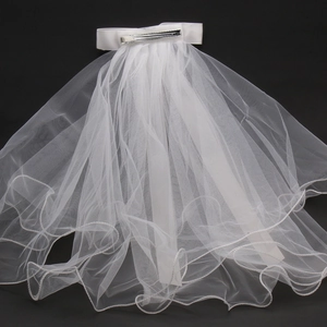 Detail of white bridal veil with elegant pearls, wavy edges and secure metal hair clip