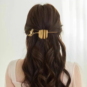 Elegant gold metal bird hair pin with cylindrical hair cuff on a model with natural lighting