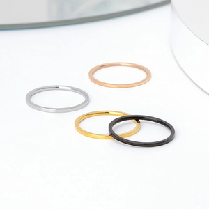 Flat minimalist titanium rings in silver, gold, rose gold and black on a white surface