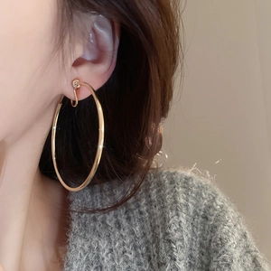 Close-up of a model wearing a large minimalist golden hoop earring with a polished finish