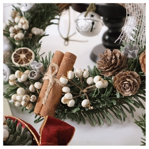 Detail of Christmas wreath with cinnamon sticks, pine cones, berries, and silver bell