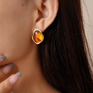 Gros plan sur boucle d'oreille géométrique en résine ambre et monture dorée sur modèle