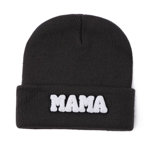 Close-up of the black knit beanie featuring white fuzzy MAMA letter embroidery