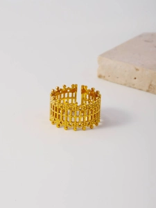 Detailed macro shot of a golden adjustable ring with unique mesh texture and dotted patterns