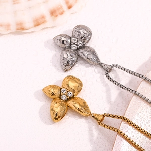 Macro shot of 18K gold and silver petal pendants with sparkling center stones and water drops