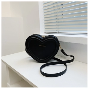 Dettaglio di una borsa a tracolla nera a forma di cuore in pelle opaca con scritte oro
