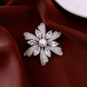 Macro detail of a silver flower brooch with zircon petals and a central white pearl