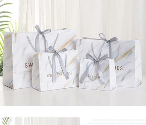 Detailed set of four white marble pattern gift bags with grey ribbons in various sizes