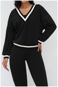 Detailed view of the V-neck color-block collar and ribbed cuffs on the black sweatshirt