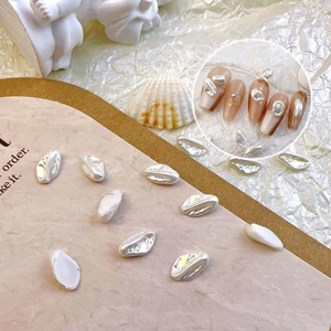 Detailed view of baroque pearl nail charms with silver accents on a vintage background