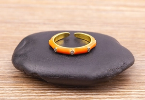 Detail of an orange enamel open ring with 18K gold plating and sparkling zircon stones