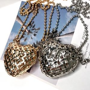 Close-up of heart-shaped hollow metal pendants in gold and silver on decorative card