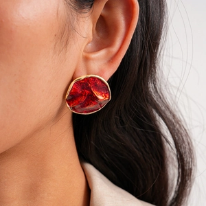 Close-up of a vintage red drip oil earring with irregular gold trim on a model's ear