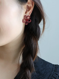 Nahaufnahme dunkelroter hohler Blumenohrstecker am Model für einen eleganten Retro-Look