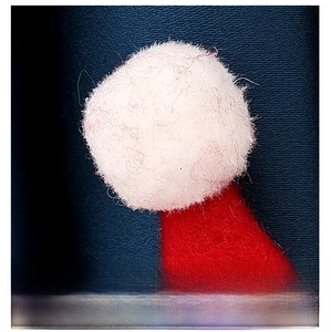 Gros plan d'un pompon blanc moelleux et de feutrine rouge sur un embrasse de rideau