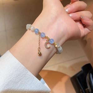 Star and moon beaded bracelet featuring cat eye stones and gold charms on wrist