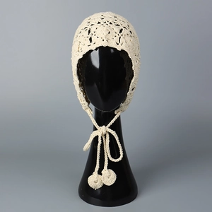 Détail d'un bonnet bohème en crochet beige avec motifs ajourés et liens à pompons faits main