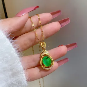 Makroaufnahme: Goldener Tropfenanhänger mit grünem Edelstein und Diamanten an feiner Kette