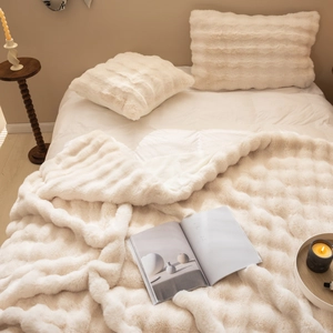 Close-up of soft beige faux fur throw blanket and pillowcase in a cozy bedroom setting