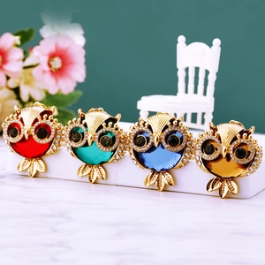 Close-up of crystal owl keychains in red, green, blue, and brown gemstone variants