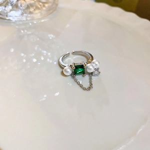 Detailed macro view of an emerald-cut green stone ring with pearls and zircons