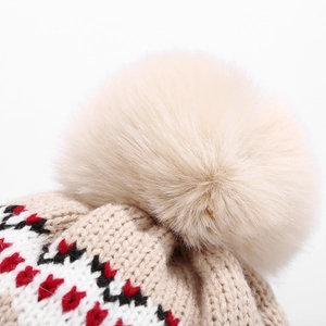 Détail du pompon en fausse fourrure et du tricot jacquard géométrique beige sur bonnet