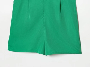 Detail view of bright green ruffled shorts showing high-quality fabric and seam texture