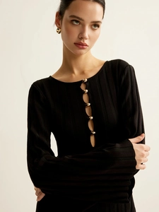 Detail of black V-neck knit dress with five gold buttons and vertical ribbed texture