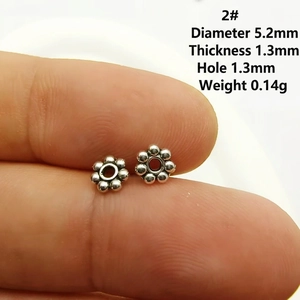 Gros plan d'intercalaires fleurs argentées de 5,2 mm pour bijoux DIY sur le bout du doigt