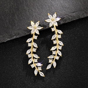 Detailed close-up of golden floral drop earrings featuring marquise-cut zircons and leaf patterns