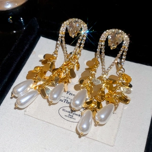 Close-up of gold tassel earrings with sparkling crystals and teardrop pearls in a jewelry box