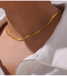 Close-up of gold-plated blade chain necklace with clover zircon pendant on a model