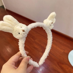 Close-up of white plush headband with cute bunny ears decoration in cream colors