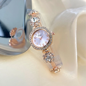 Detail of rose gold quartz watch with rhinestones on silk fabric background