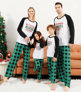 Family matching pajamas set with Christmas slogan and green plaid pants in cozy home setting
