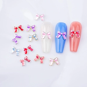 Détail macro de nœuds métalliques colorés pour ongles avec bords dorés sur fond marbre