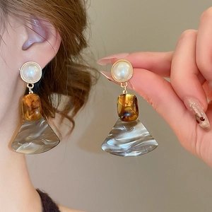 Detail showing resin fan-shaped drop earrings with marble texture and pearl studs