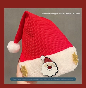 Detail view of a red knitted Christmas hat with plush white brim and Santa Claus patch
