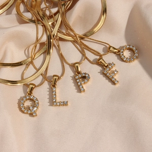 Macro view of five 18K gold plated snake chain necklaces with zircon letter pendants