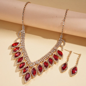 Close-up of luxury gold necklace and earrings set with red stones and sparkling tassels