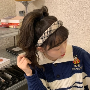 Elegant woman wearing a padded beige plaid headband in a retro academic style setting