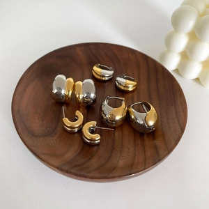 Two-tone gold and silver minimalist drop earrings on a dark wooden display tray