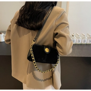 Detail of a matte black doctor bag featuring a chunky gold chain and embossed logo emblem
